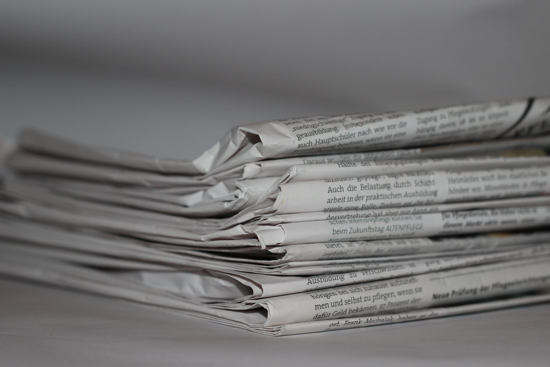 A folded student newspaper opinion section resting on a wooden desk beside reading glasses and a coffee mug